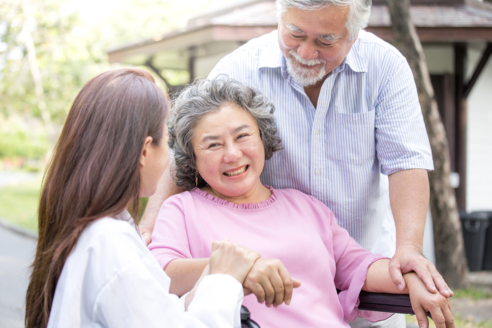 Caregivers talking to a patient sitting on a wheelchair